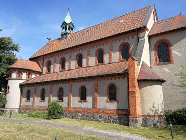Historisches Kirchengebäude mit Turm und rotem Dach.