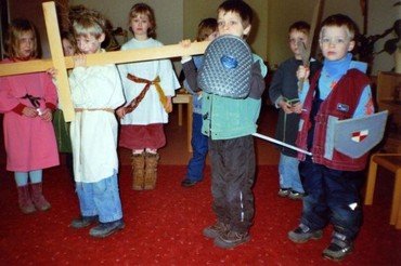 Kinder spielen eine religiöse Szene mit einem Kreuz.