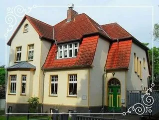 Pfarrhaus mit rotem Dach und grüner Tür.