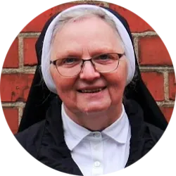 Lächelnde Nonne im Habit mit Brille.