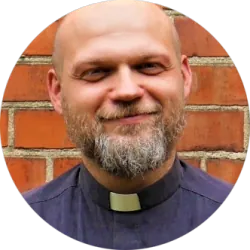 Lächelnder Priester mit Bart und Kollar.