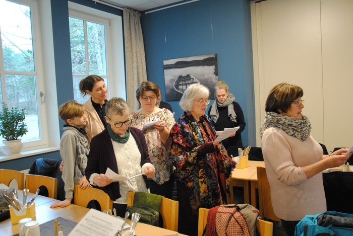 Chormitglieder aller Altersgruppen singen gemeinsam von Notenblättern.