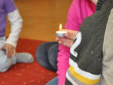 Kind hält eine brennende Kerze.