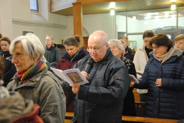 Mann liest mit Mikrofon während eines Gottesdienstes.