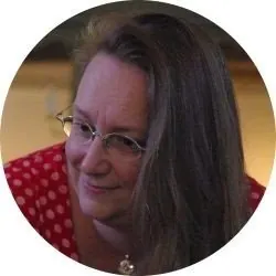 Lächelnde Frau mit langen Haaren und Brille.